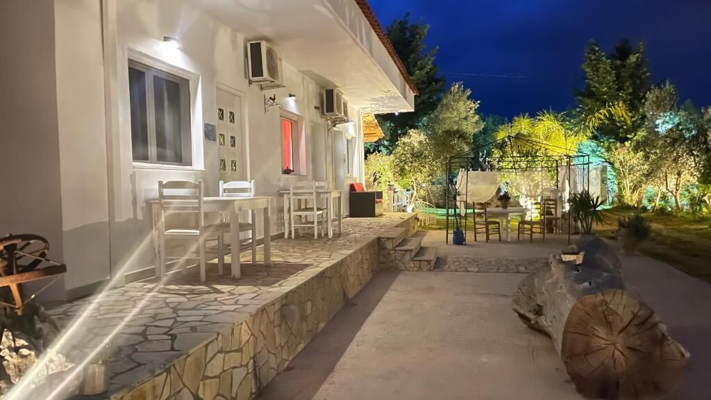 A well-lit outdoor area with stone flooring, a wooden log, and outdoor seating.