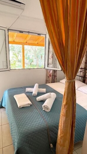 Ein Schlafzimmer mit einem Bett, zwei Fenstern und einem Vorhang.