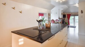 Een moderne keuken met een zwart aanrecht, witte kastjes en uitzicht op de eetruimte.