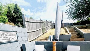 A patio area with two white cushioned chairs, a patterned rug, and a wood-burning stove. - modern Bungalow with hot tub, garden, bbq & Netflix 10 min drive to city centre (Southampton)