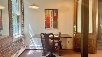 A dining area with a table, chairs, pendant lights, and a framed artwork on the wall.