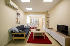 A modern living room with a sofa, a coffee table, a TV, and a bookshelf. - Bright 1bdr Apartment in Top Center (Sofia)