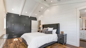 Ein Schlafzimmer mit einem großen Bett, dunklem Holzboden und einer weißen Decke.
