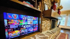Un téléviseur à écran plat fixé à un mur en pierre, diffusant différents programmes pour enfants.