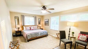 Une chambre à coucher comprenant un lit, une chaise, un bureau, un ventilateur de plafond et une fenêtre.