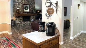Une cuisine moderne avec un mur d’accent en pierre, un panneau indiquant l’emplacement du bar à café et une machine à café posée sur le comptoir.