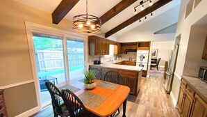 Une cuisine spacieuse dotée de meubles en bois, d’un îlot central et d’un coin repas avec une table et des chaises.