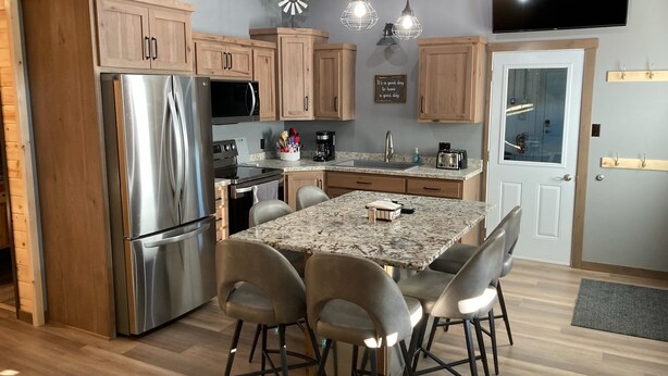 A modern kitchen with wooden cabinets, stainless steel appliances, a granite countertop, and pendant lighting. - Newly built in Devils Lake, Perfect for Fishing or Relaxing (Devils Lake)