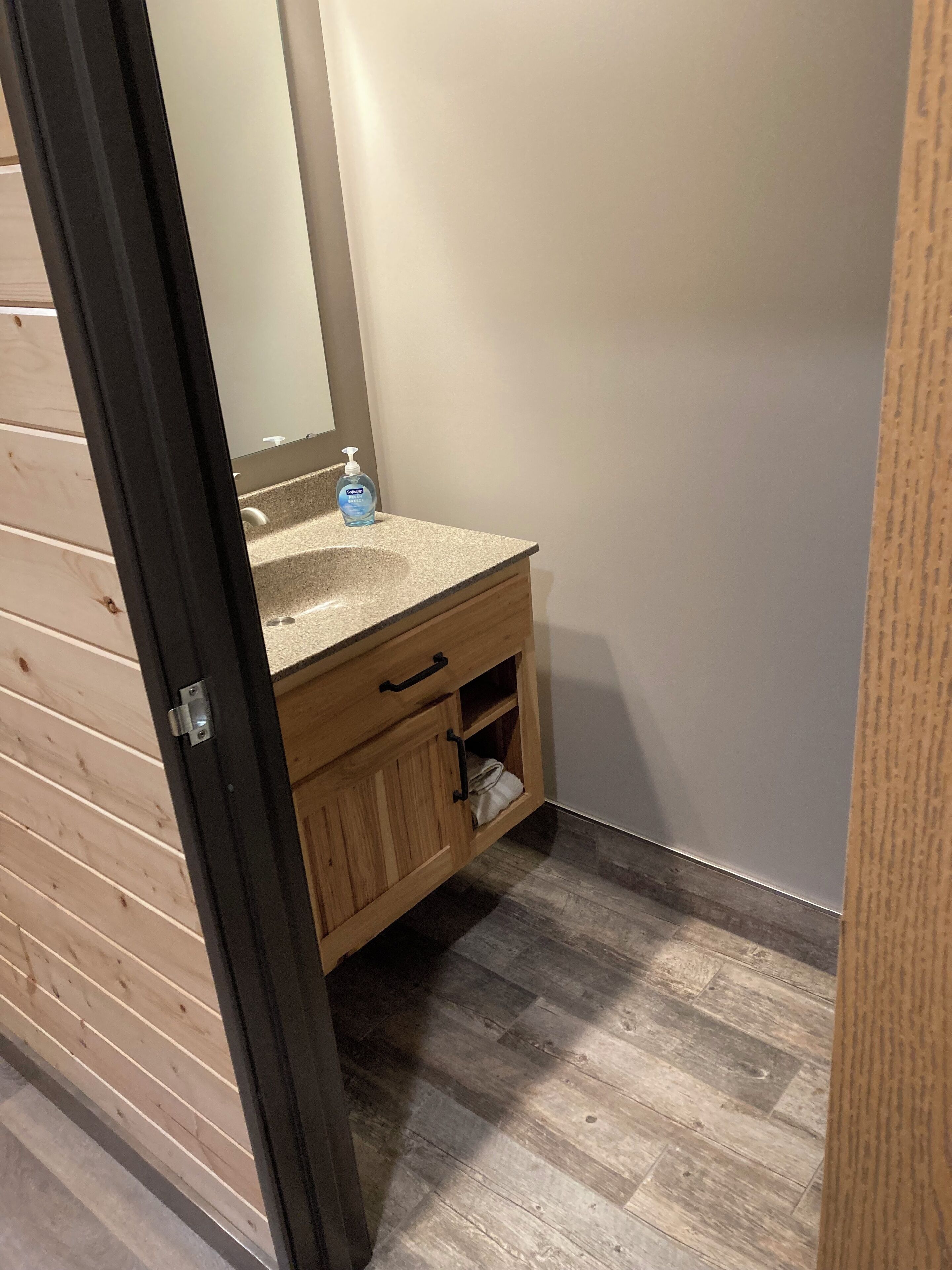 Un baño con tocador de madera, espejo y dispensador de gel antibacterial.