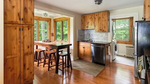 A kitchen with wooden cabinets, a stainless steel sink, and a black refrigerator.