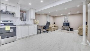 A modern kitchen with white cabinets, a built-in oven, and a dining area with a table and chairs. - Hidden Gem: Spacious Basement (Milton)