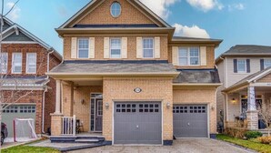A two-story house with a garage, a front porch, and a brick facade. - Hidden Gem: Spacious Basement (Milton)