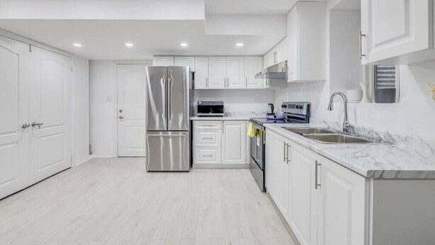 A modern kitchen with white cabinets, stainless steel appliances, and a marble countertop. - Hidden Gem: Spacious Basement (Milton)