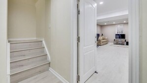 A spacious living area with a staircase, a sofa, and a television. - Hidden Gem: Spacious Basement (Milton)