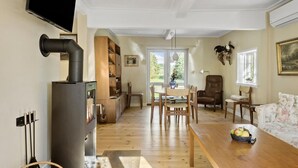 Un salon spacieux doté d’une cheminée, de meubles en bois et d’un coin repas offrant une vue sur l’extérieur.