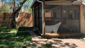 A covered outdoor area with a wooden deck, a metal railing, and a view of a house in the background.