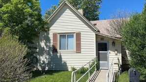 A small, single-story building with a front door, a small porch, and a mailbox.