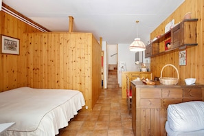 Ein Zimmer mit Holzboden, einem Bett, einer Küchenzeile und einem Esstisch.