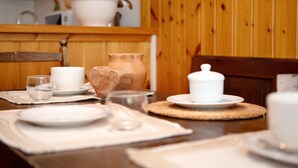 A dining table set with white plates, cups, and a pitcher, with a wooden chair and a woven placemat. - Apartment 'Larice' with Mountain View, Private Terrace and Shared Garden (Pila)