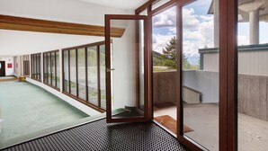 A room with large sliding glass doors, a green carpet, and a view of a mountainous landscape. - Apartment 'Larice' with Mountain View, Private Terrace and Shared Garden (Pila)