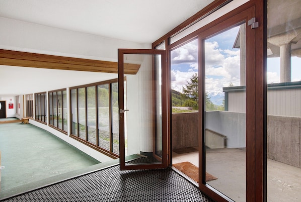A room with large sliding glass doors, a green carpet, and a view of a mountainous landscape.