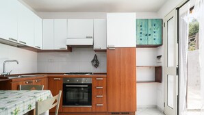 A kitchen with white cabinets, a wooden countertop, a stove, and a teal cabinet with heart designs.