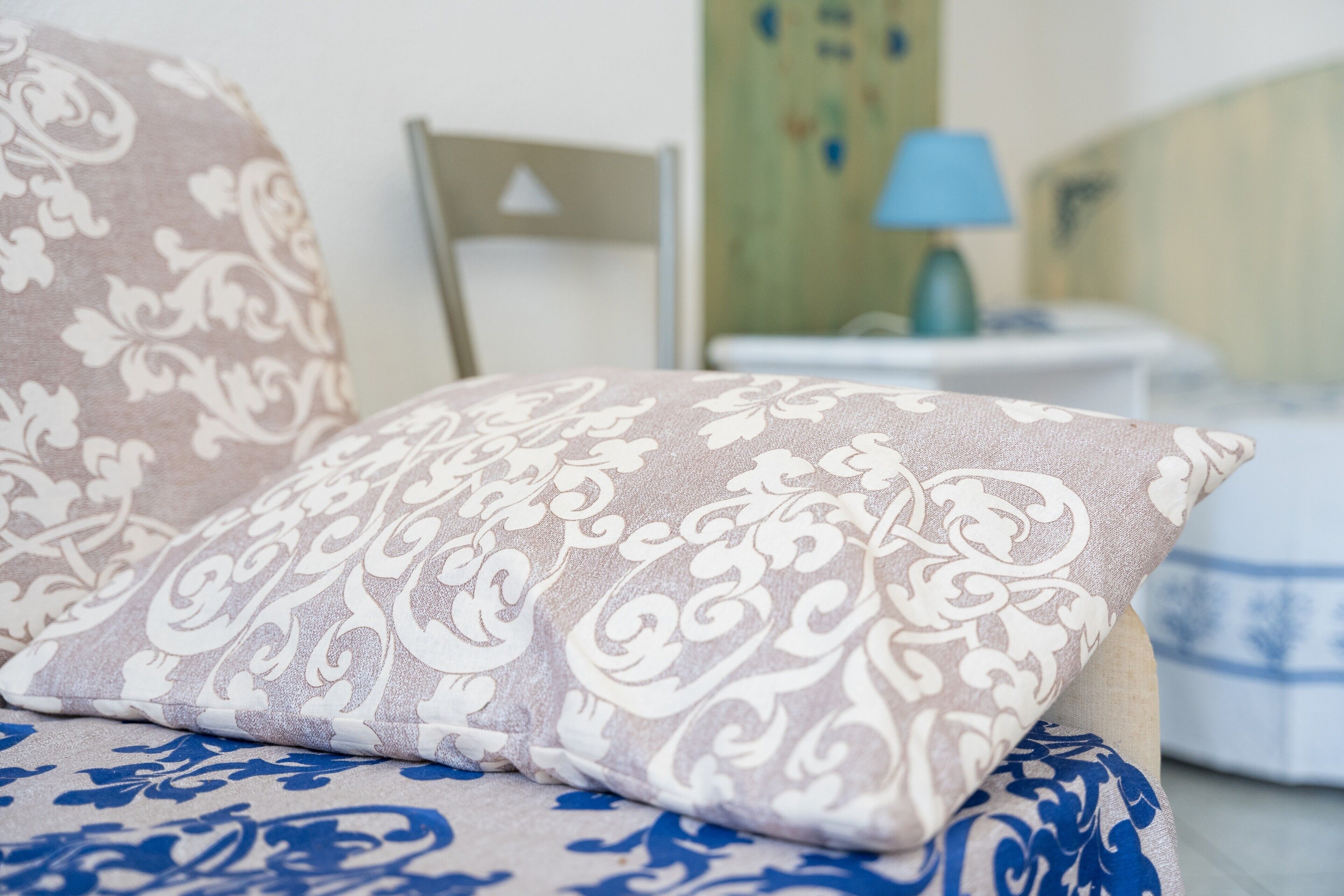 Un lit avec des coussins à motifs et une couvre-lit bleue et blanche.