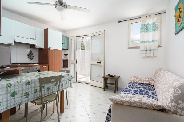 A compact living space with a dining area, kitchenette, and a sofa.