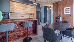 Une cuisine moderne avec des meubles en bois, un four encastré et un coin bar avec des tabourets.