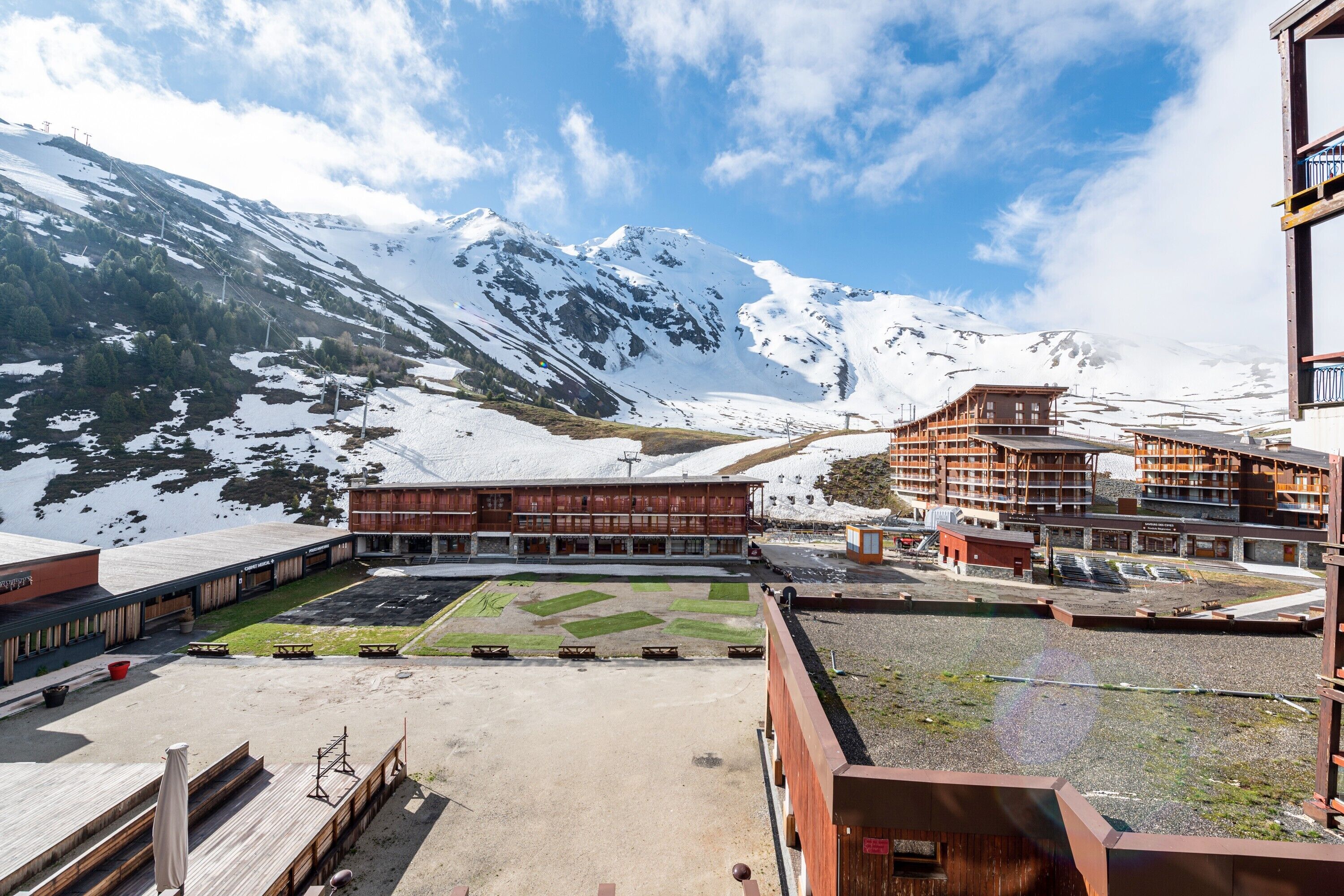 Eine Berglandschaft mit schneebedeckten Gipfeln, ein Gebäude mit Holzfassade und einem klaren Himmel.