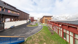Un edificio con una entrada en forma de carril, una cerca azul y una vista de montañas nevadas al fondo.