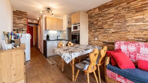 Una cocina compacta con armarios de madera, un microondas y un comedor con mesa y sillas.