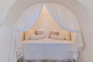 A bed with a canopy, pillows, and a lace trim.