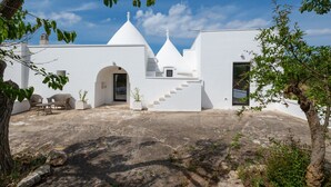 A white building with a staircase leading to a door, surrounded by greenery and a clear sky. - Villa 'Trullo Bianco Molillo' with Private Garden (Ostuni)