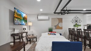 A modern hotel room with a bed, desk, chairs, a TV, and artwork. - Brand NEW Centrally Located with FREE parking and PET friendly!! (Saint Paul)