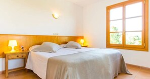 Un dormitorio con una cama, lámparas de noche, una ventana y un aplique de pared.
