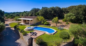A house with a swimming pool, a covered patio, and a stone wall.