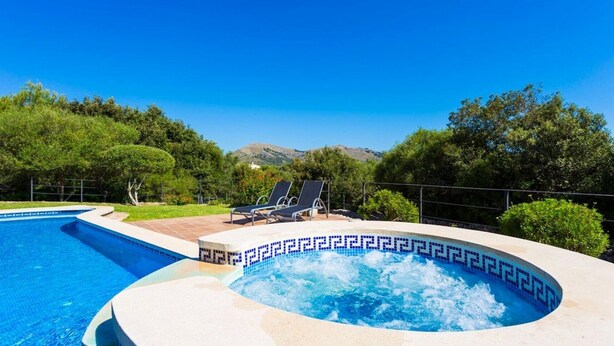 Una piscina con hidromasaje, sillas de descanso y vistas a montañas.