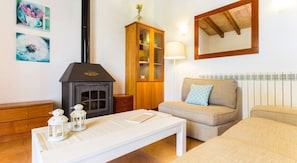 A cozy living room with a fireplace, a sofa, a table with decorative items, and a cabinet.