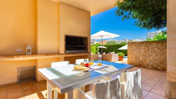 Un patio al aire libre con una mesa lista para el desayuno, una parrilla y vistas a la ciudad.