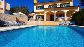 Una piscina con sillas de descanso y un muro de piedra.