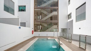A swimming pool with a glass railing, a fire safety sign, and a staircase leading to an upper level. - Apartment 'Apartamento Pachimon' with Shared Pool, Wi-Fi and Air Conditioning (Conil de la Frontera)