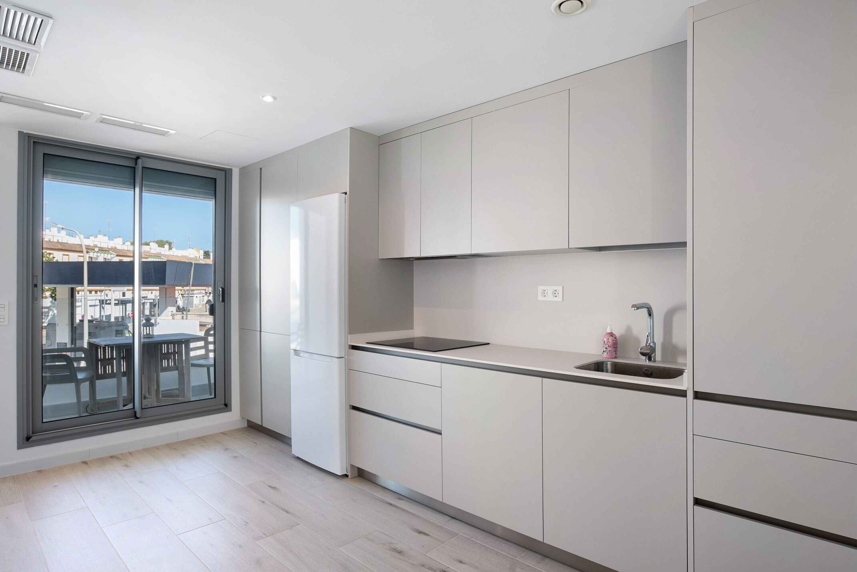 Una cocina moderna con un ventanal grande, un lavaplatos integrado y un refrigerador.