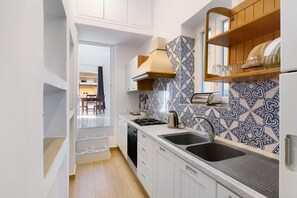 A modern kitchen with white cabinets, a black sink, a stove, and patterned backsplash tiles.