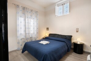 A bedroom with a bed, a nightstand, a lamp, a window with curtains, and a wall-mounted picture. - Apartment 'Penisola  1' with Shared Terrace, Wi-Fi and Air Conditioning (Vico Equense)