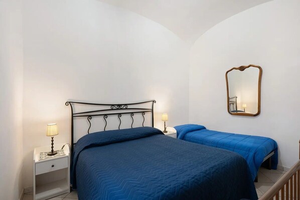 Une chambre à coucher avec un lit, des tables de chevet, des lampes, un miroir et un escalier.
