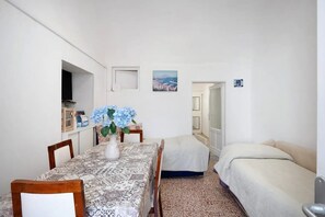 Une petite chambre propre, avec une table à manger, deux lits simples et une vue sur la ville.