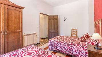 Un dormitorio con dos camas, un armario, un radiador y una puerta que da a otra habitación.