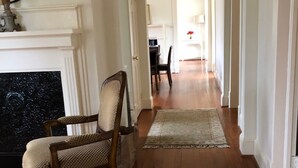 A hallway with wooden flooring, a fireplace, and a chair.