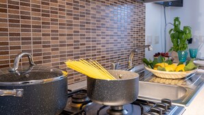 Une cuisine équipée d’une cuisinière, de casseroles et d’un saladier rempli de fruits.